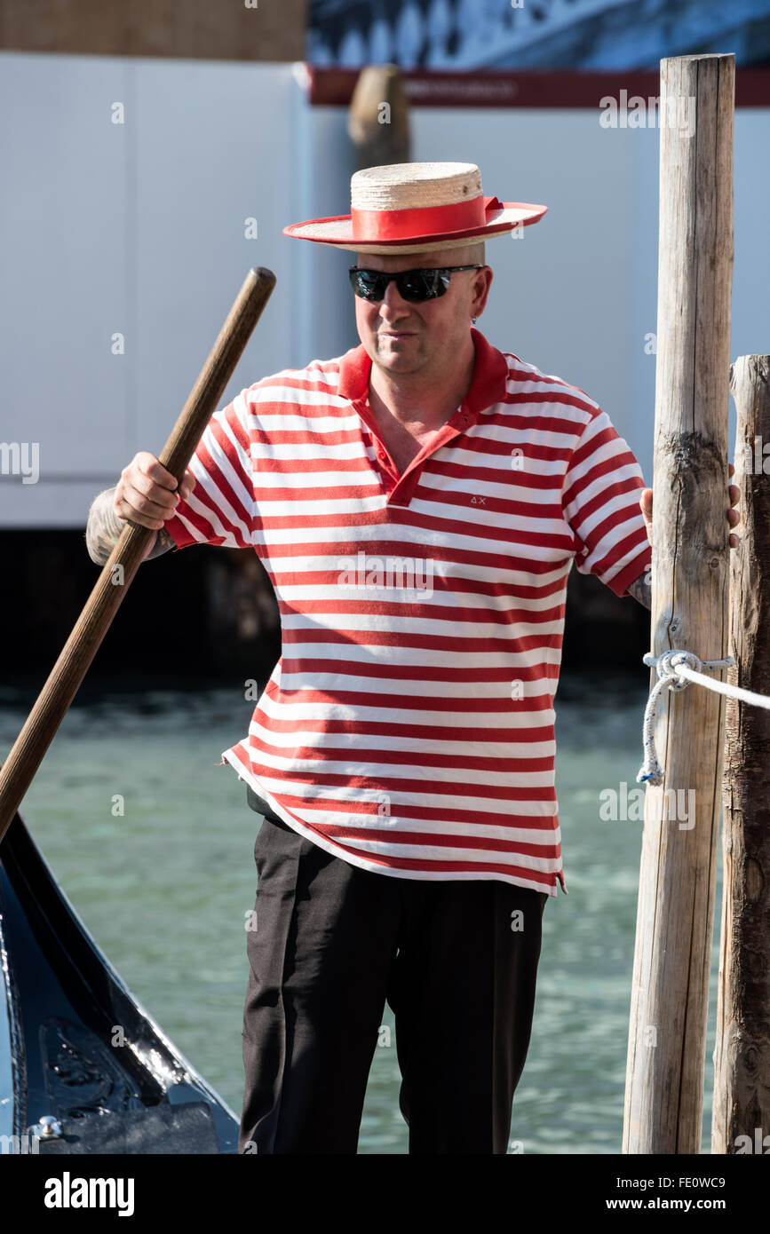 A gondoliere wearing his red & white striped shirt and boater with a red band in Venice, Italy Stock Photo