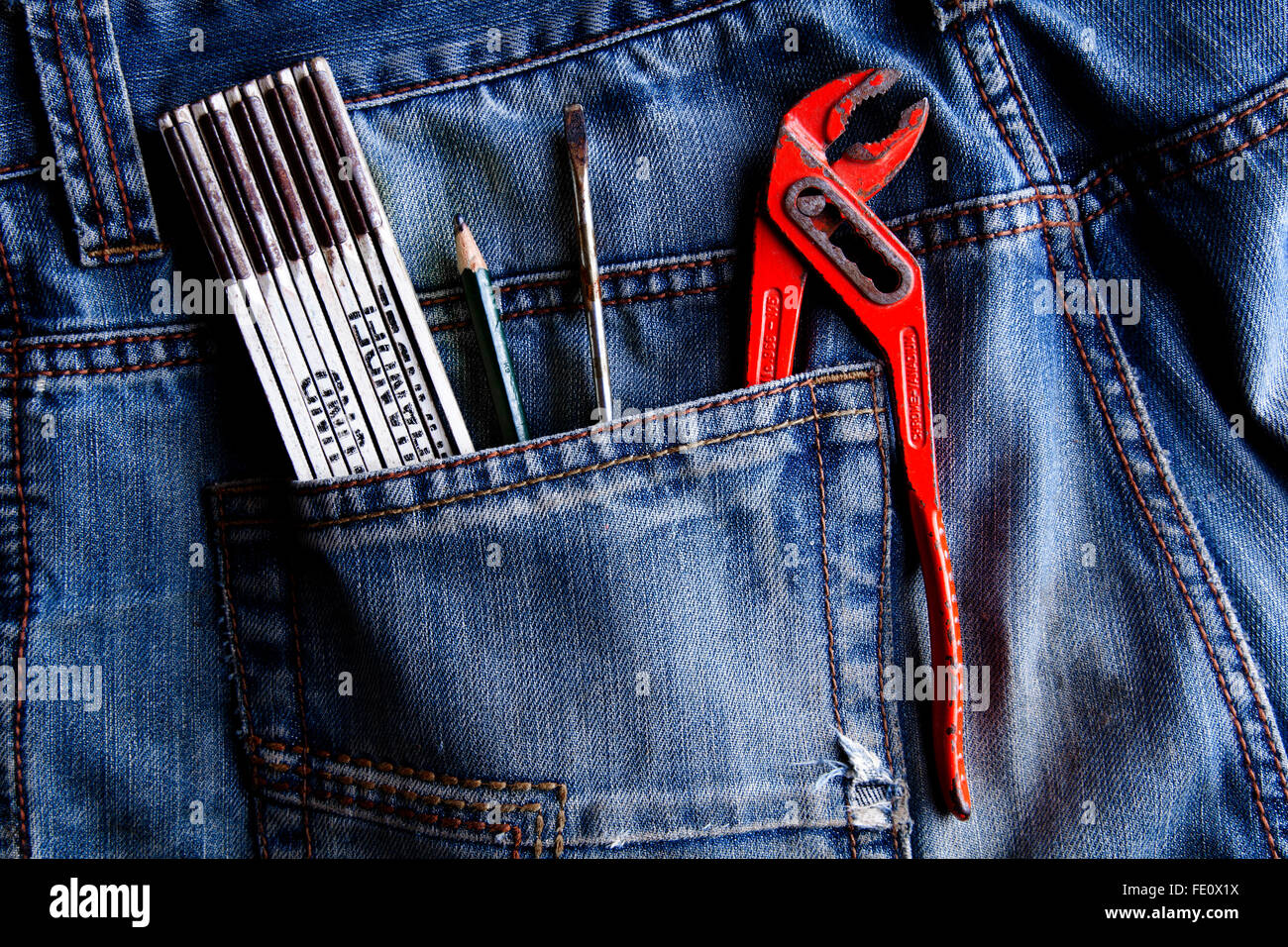 Ruler, pencil, screwdriver, pipe wrench, in a jeans pocket Stock Photo
