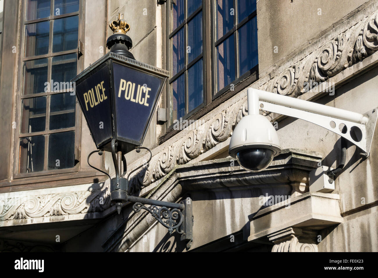 A modern CCTV camera next to a traditional police blue lamp sign, on a police station in London. Stock Photo