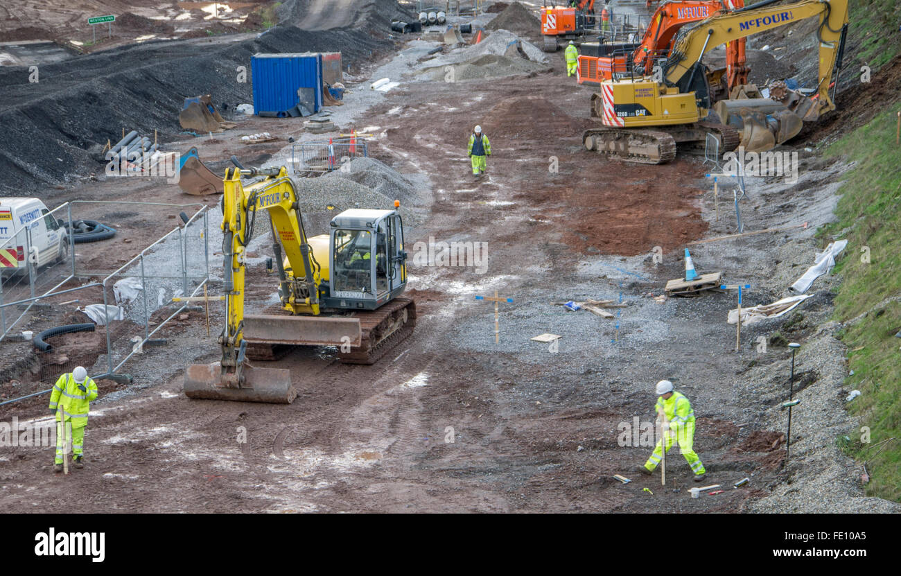 Diggers working with men in safety jackets and helmets placing wooden markers. Stock Photo