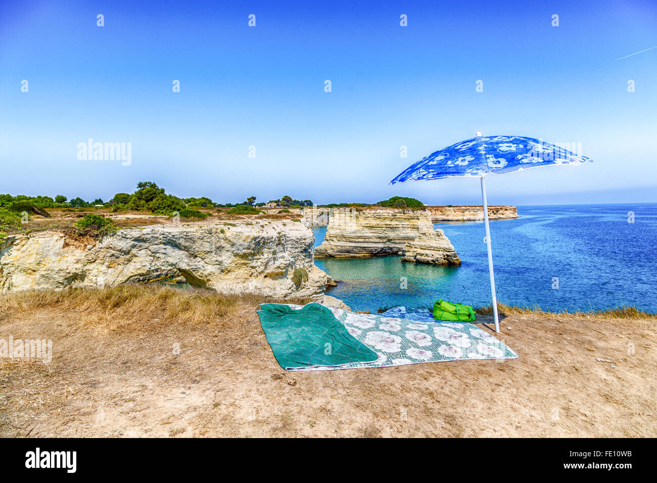 Umbrella and rocky stacks of Santo Andrea on the coast of Salento in Puglia in Italy Stock Photo