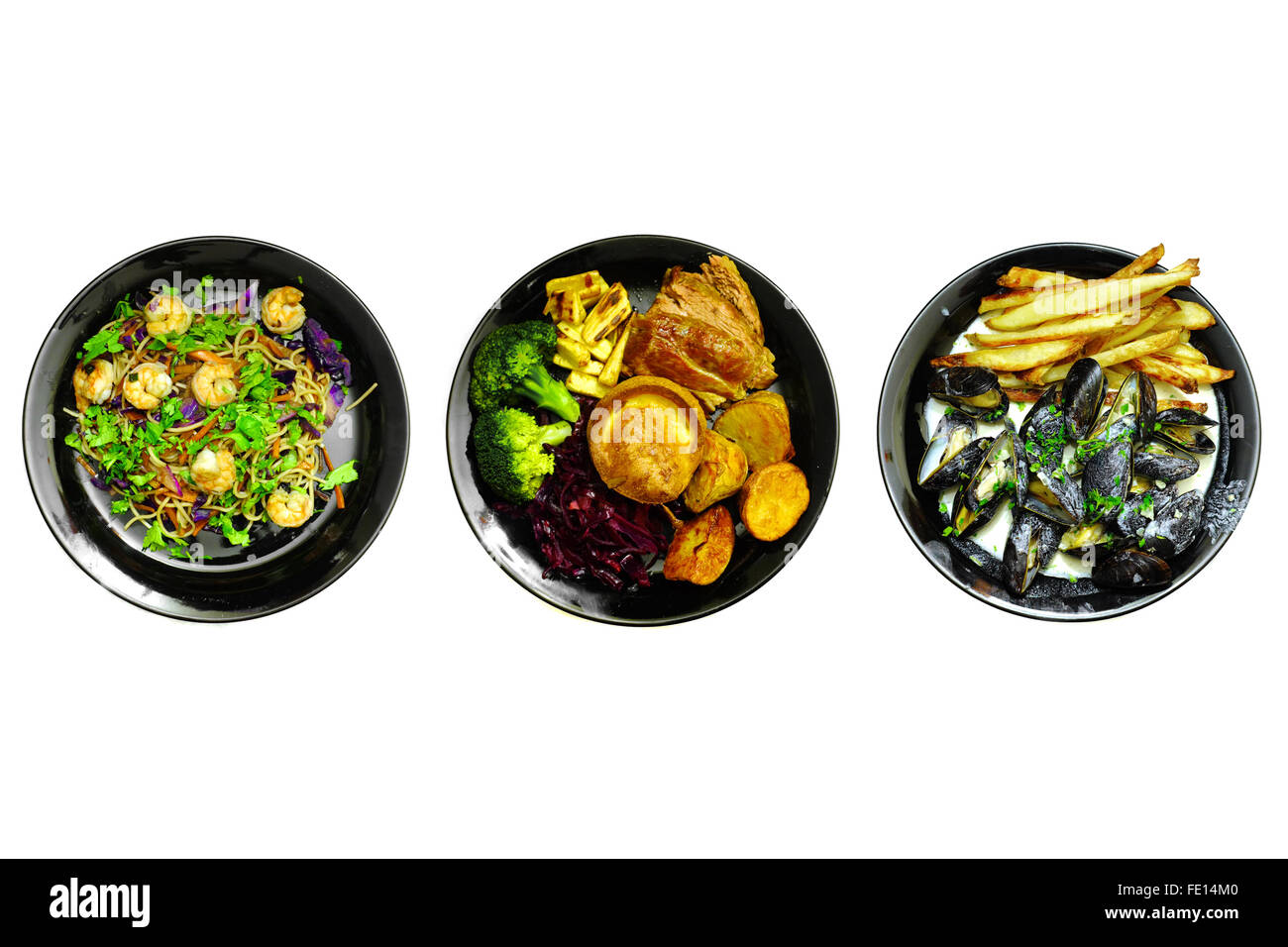 Different meals on black plates photographed against a white background