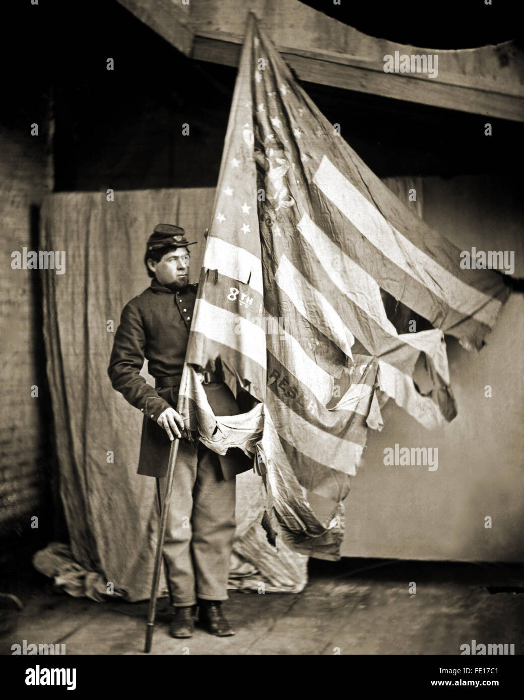 Battle tattered flag of the Pennsylvania Infantry held by a young Union Civil War soldier. Stock Photo