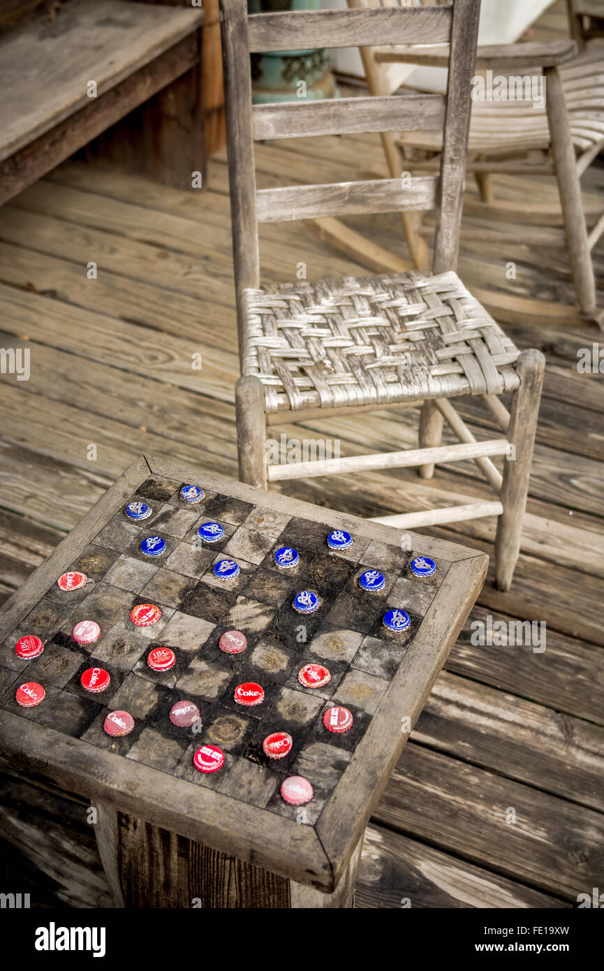 Checkers made from old soft drink bottle caps. an old wooden porch with a rickity old chair