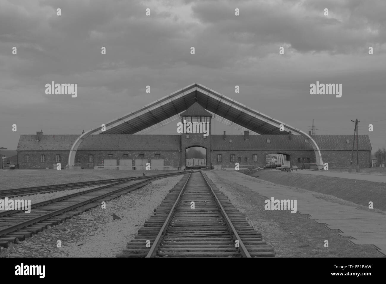 Black and white image of railway line leading to the entrance of the Nazi death camp at Auschwitz in Poland in winter Stock Photo