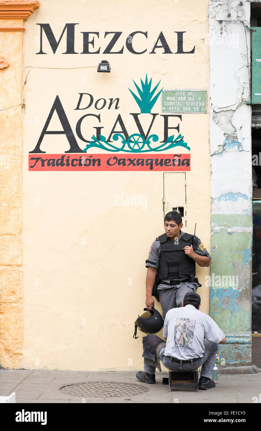 Policeman getting shoes shined on a city sidewalk, Oaxaca, Mexico Stock Photo
