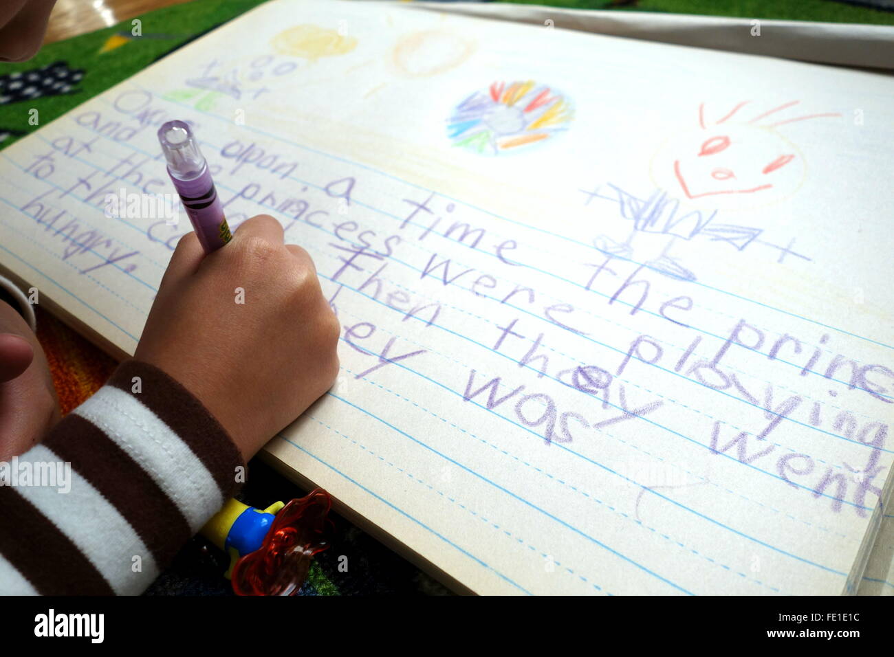 A young child writing a story on a drawing pad Stock Photo