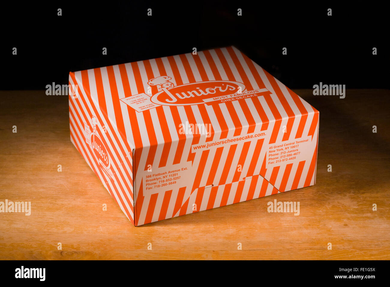 An iconic orange striped Junior's Cheesecake Box from their Brooklyn flagship restaurant in New York City on a wooden tabletop Stock Photo