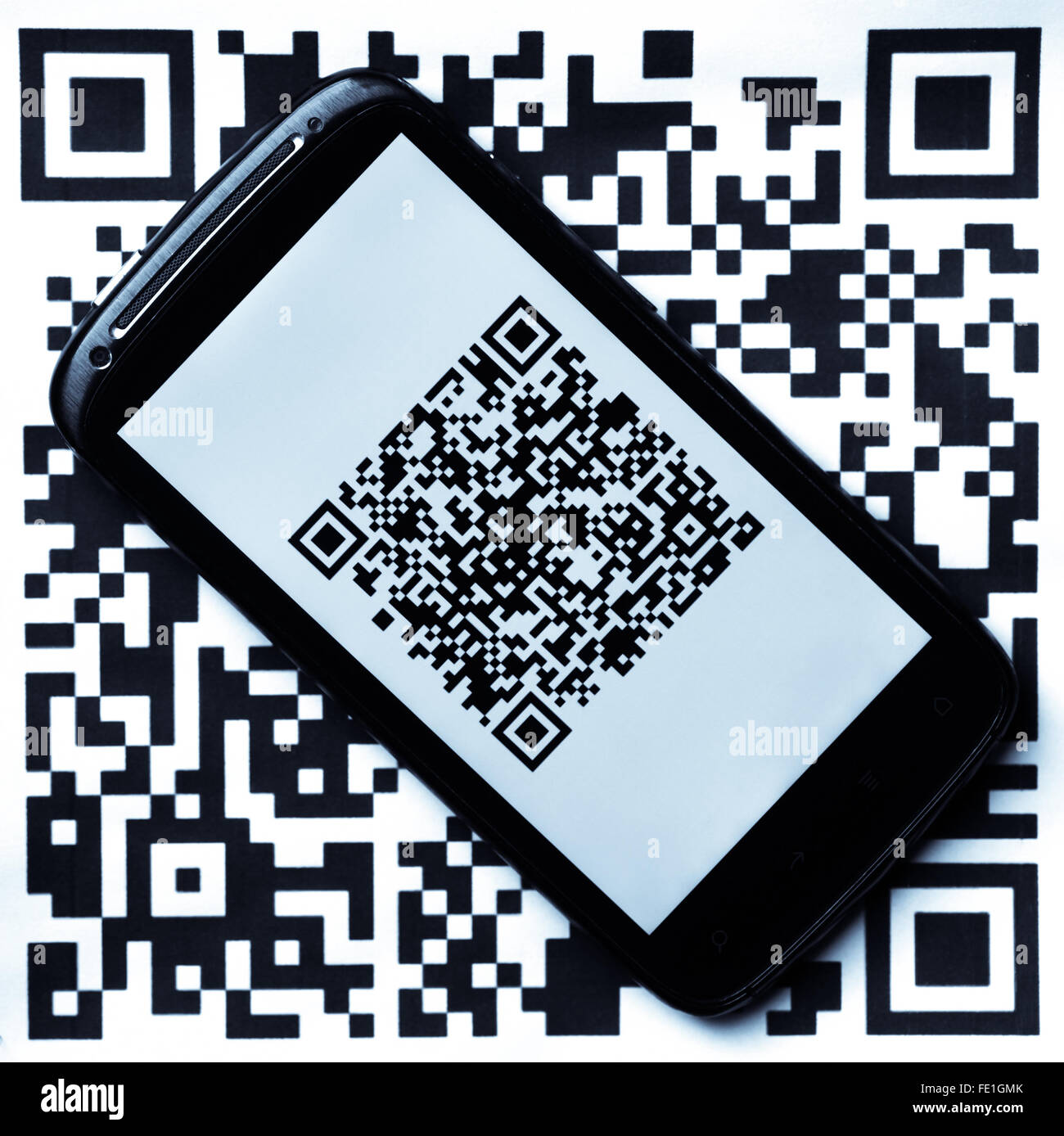 A mobile phone next to a QR code printed on paper. If scanned, the QR