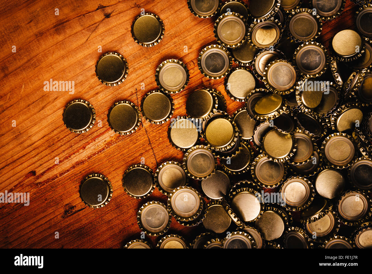 Large pile of beer bottle caps on rustic oak wooden desk Stock Photo