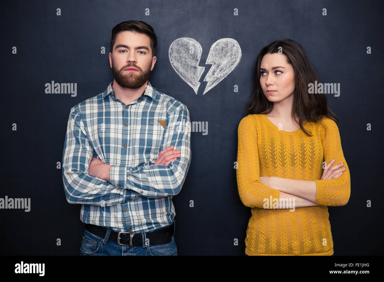 Portrait of young couple after argument standing separately with hands ...