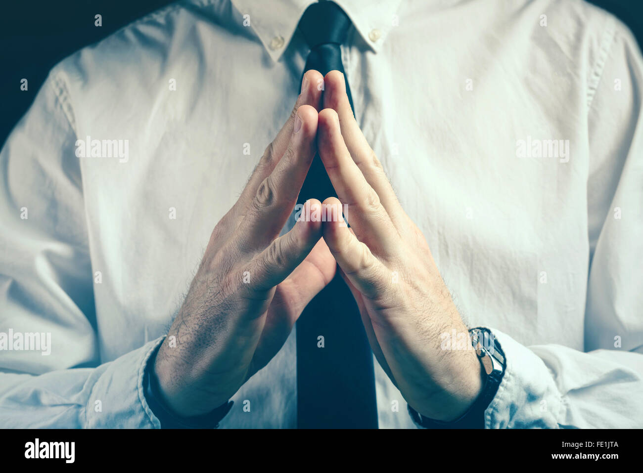 Confident businessman steepling gesture, fingers pressed in steeple position as sign of confidence, retro toned image. Stock Photo