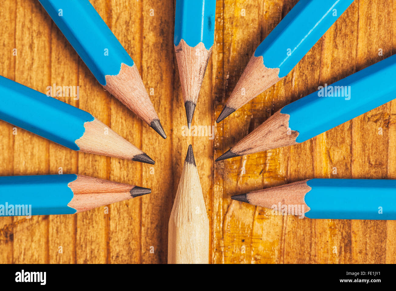 Standing out from the crowd, being different concept, surrounded by adversity, judging the odd one, wood pencils on desk Stock Photo