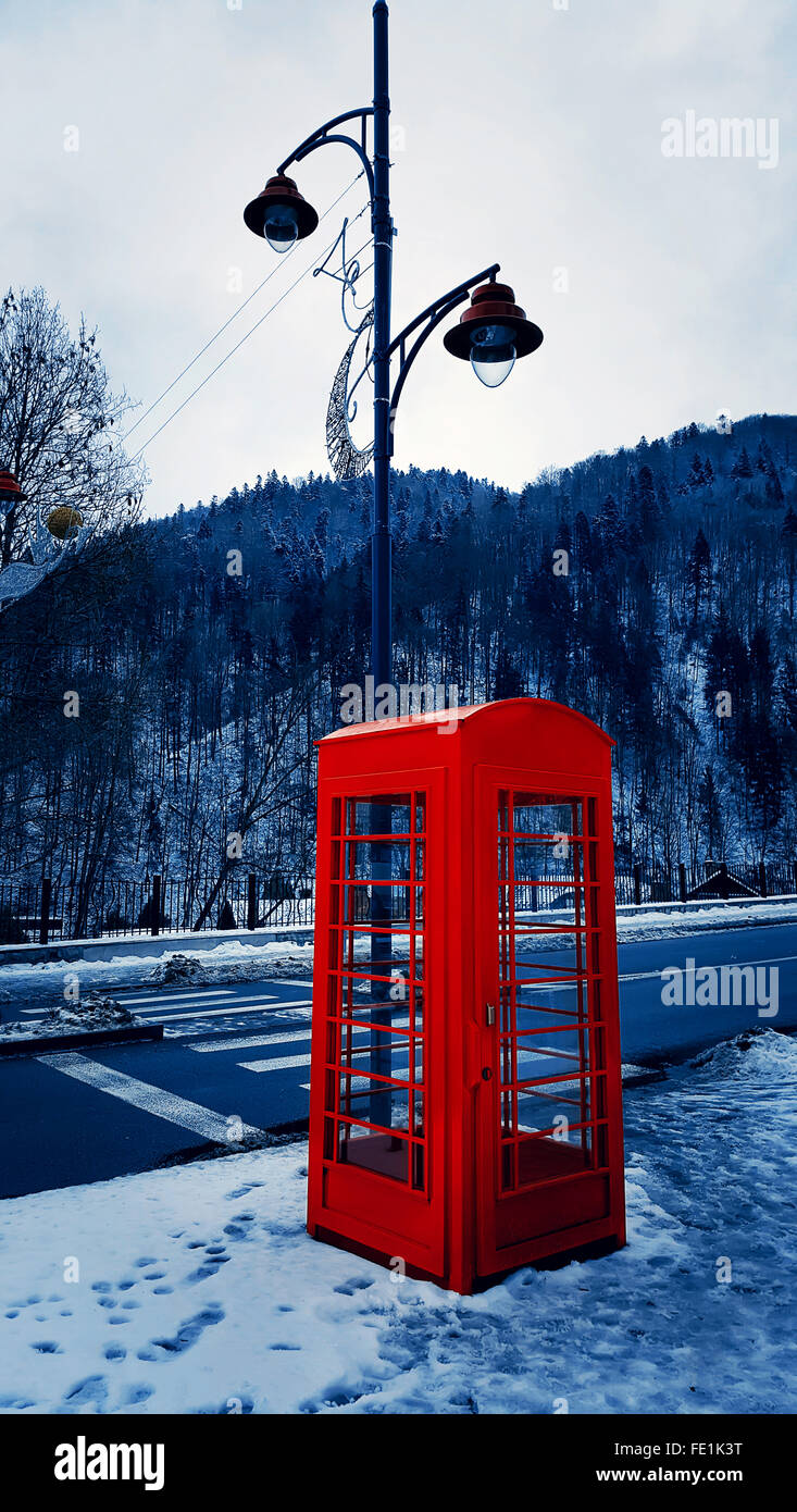 Classic red British telephone box on the snowy street in Sinaia, Carpathian Mountains, Romania Stock Photo