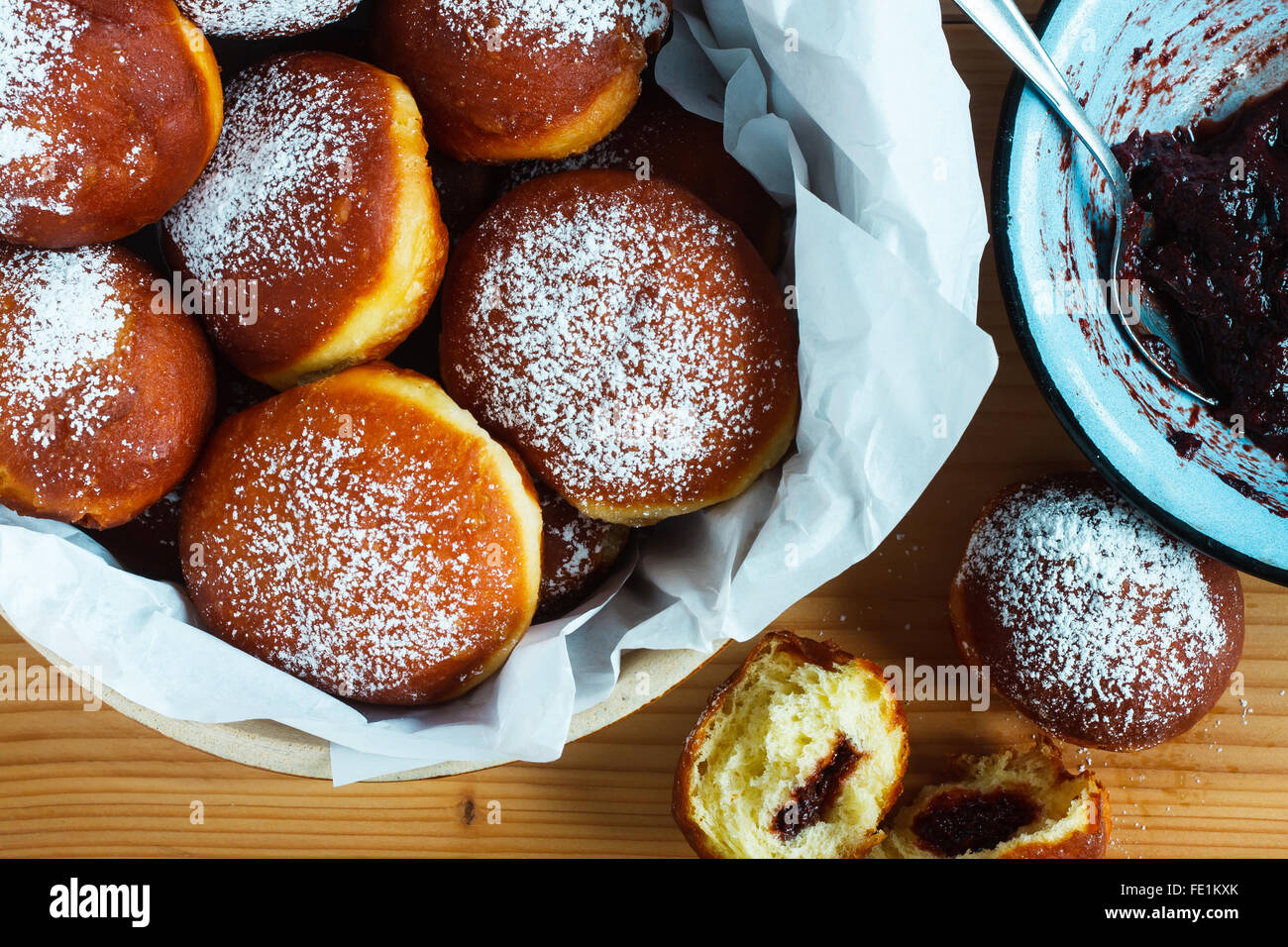 Homemade donuts filled with rose marmalade on wooden table. Rustic style Stock Photo