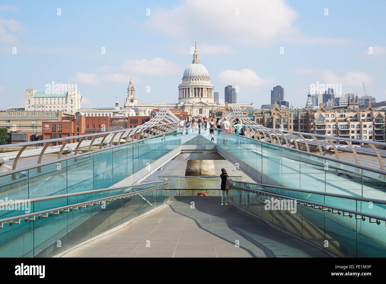 Millennium bridge with people walking and St Paul cathedral in a summer morning in London Stock Photo