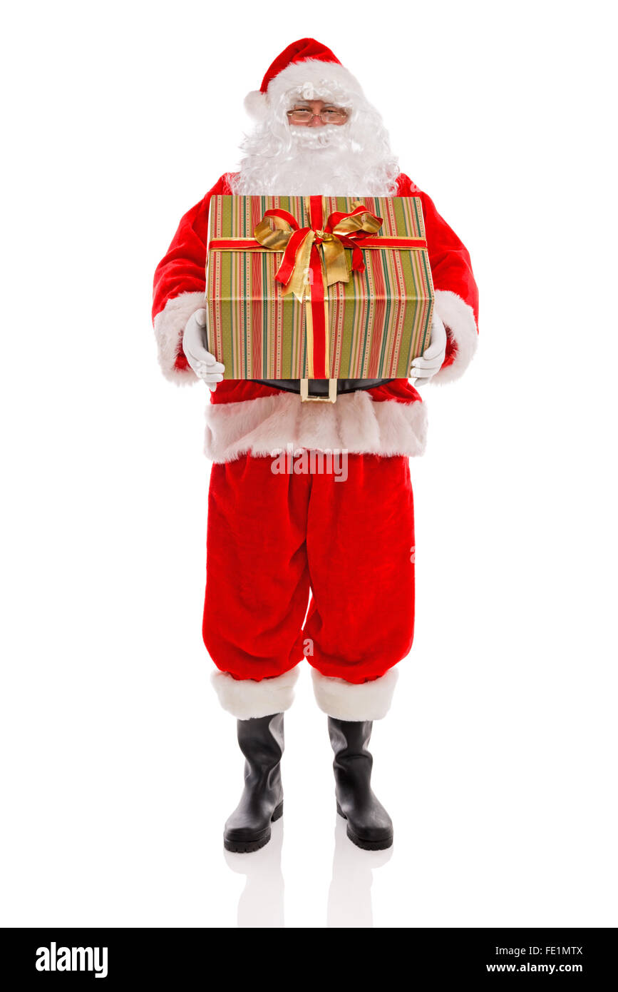 Father Christmas or Santa Claus holding a large gift wrapped present with ribbons and bow, isolated on a white background. Stock Photo