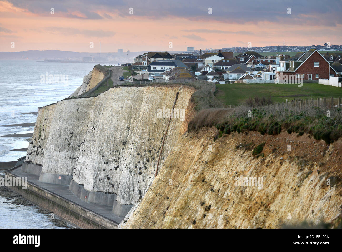 Houses close to the edge of chalk cliffs in Peacehaven, near Brighton, UK, at sunset Stock Photo