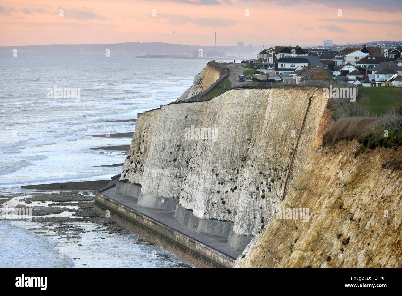 Houses close to the edge of chalk cliffs in Peacehaven, near Brighton, UK, at sunset Stock Photo