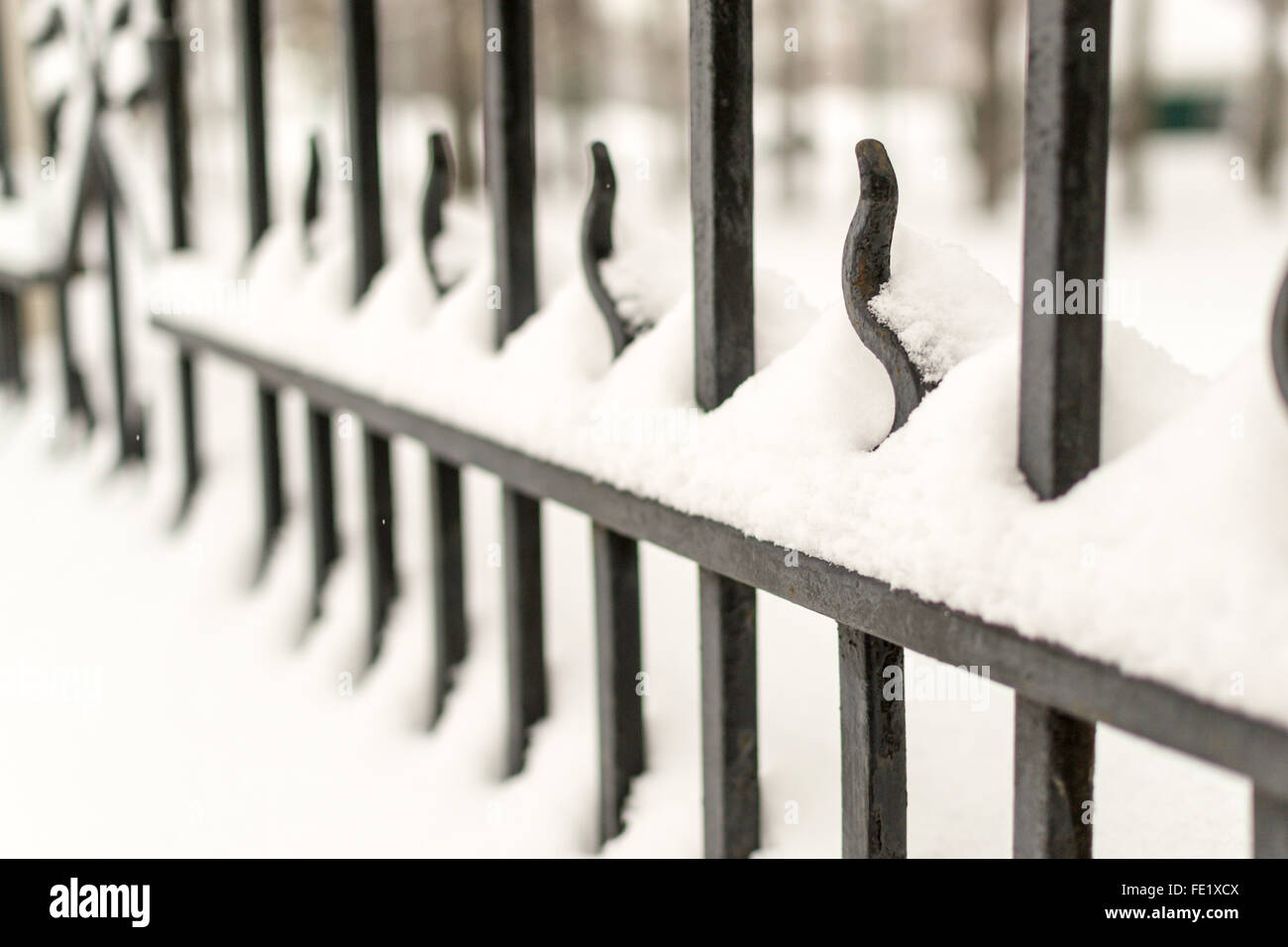 Strong black cast iron fence with railings covered in fresh winter snow ...