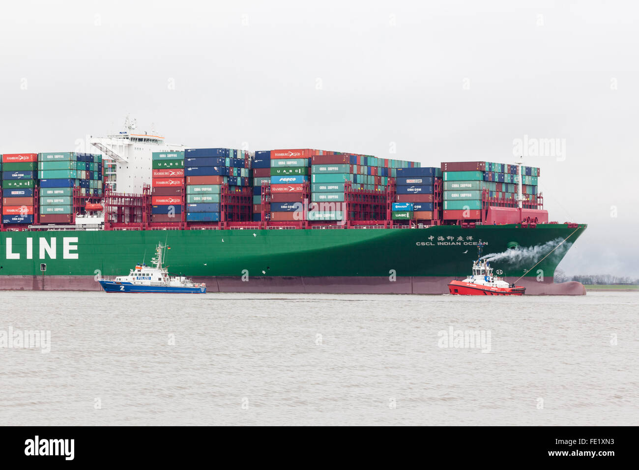 Grünendeich, Germany - February 4th, 2016: Tugboat trying to rescue Chinese container vessel CSCL Indian Ocean that ran aground in the Elbe river, police boat in front. Stock Photo