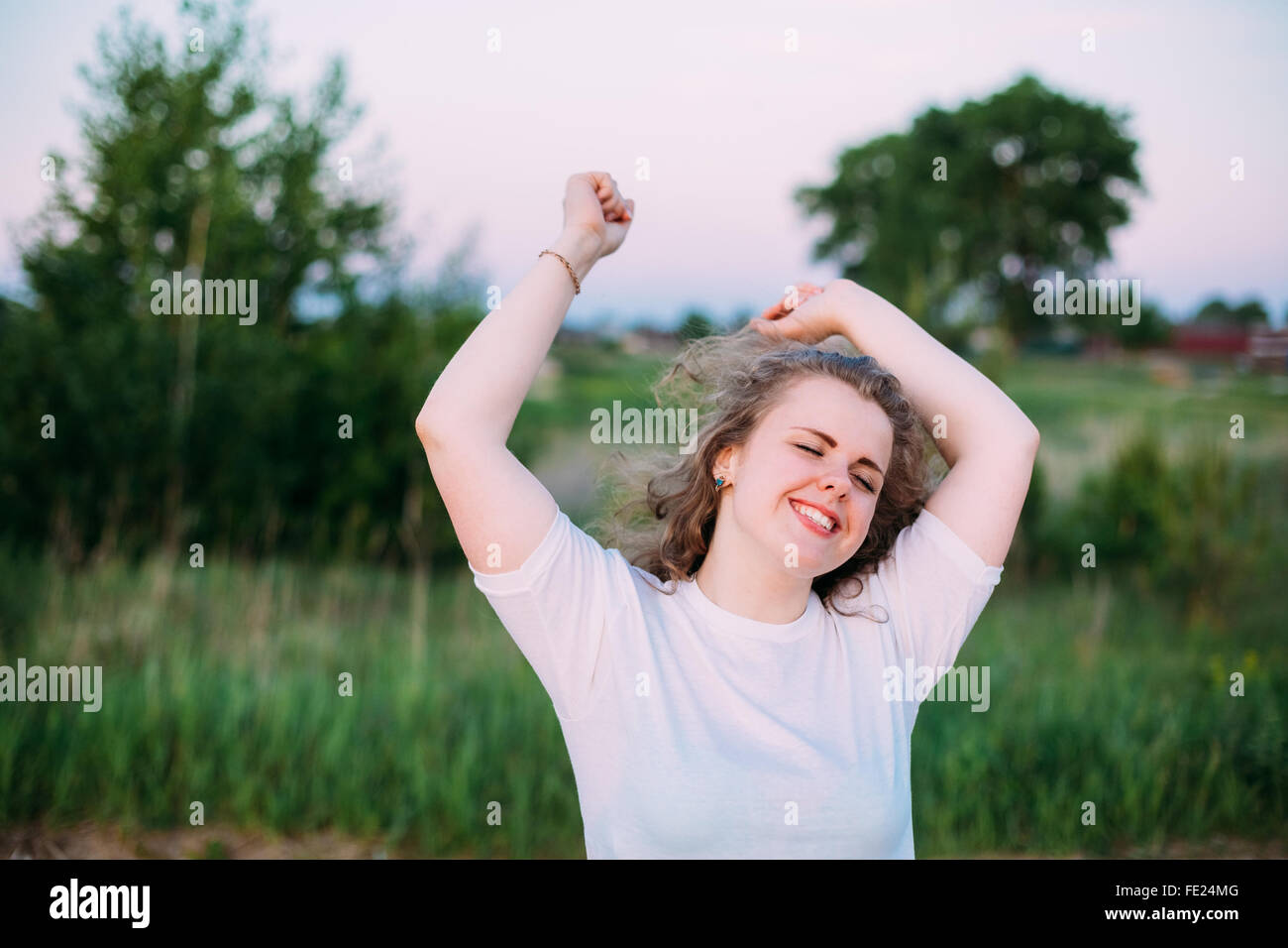 Pretty Caucasian Plus Size Young Woman In White Shirt Dancing on Summer green Field Meadow Background. Summer, Outdoor Portrait Stock Photo
