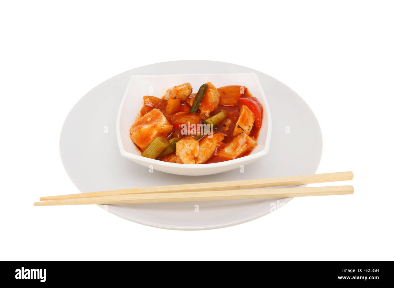 Chinese meal, Chicken Kung Po, in a bowl on a plate with chopsticks, isolated against white Stock Photo
