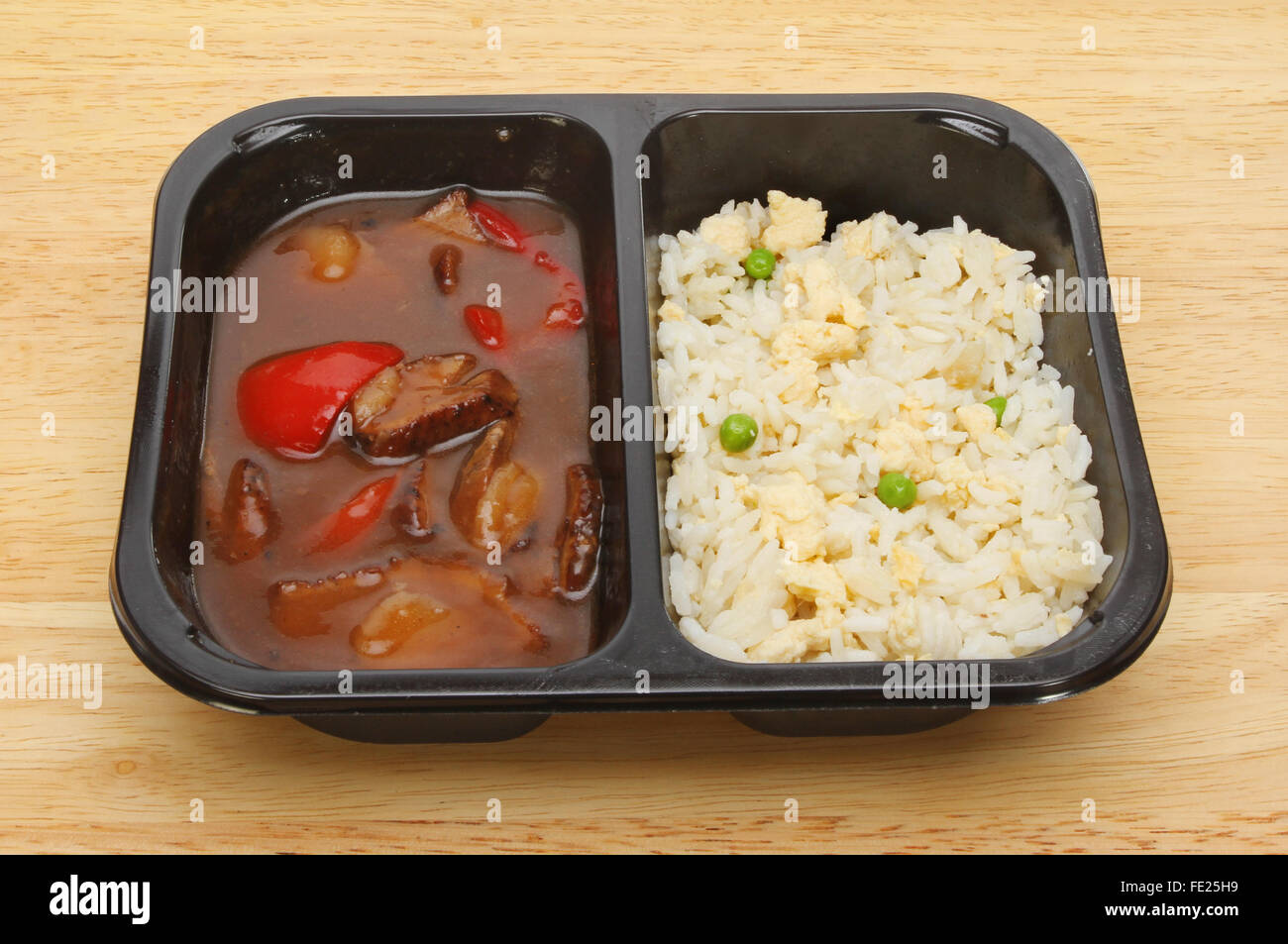 Oriental microwave meal, duck in plum sauce with egg fried rice in a plastic carton on a wooden board Stock Photo