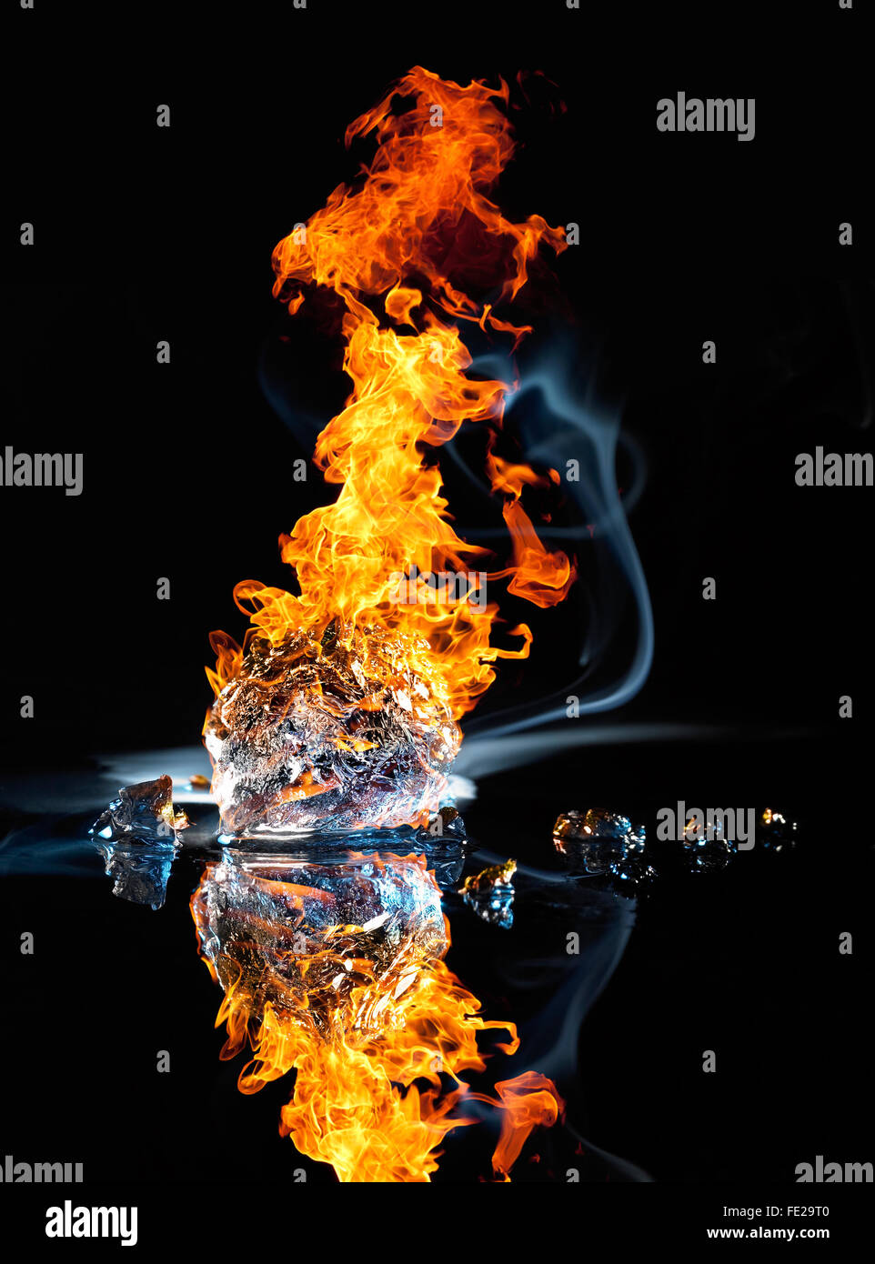 studio photography of a burning ice crystal and smoke in black reflective back Stock Photo