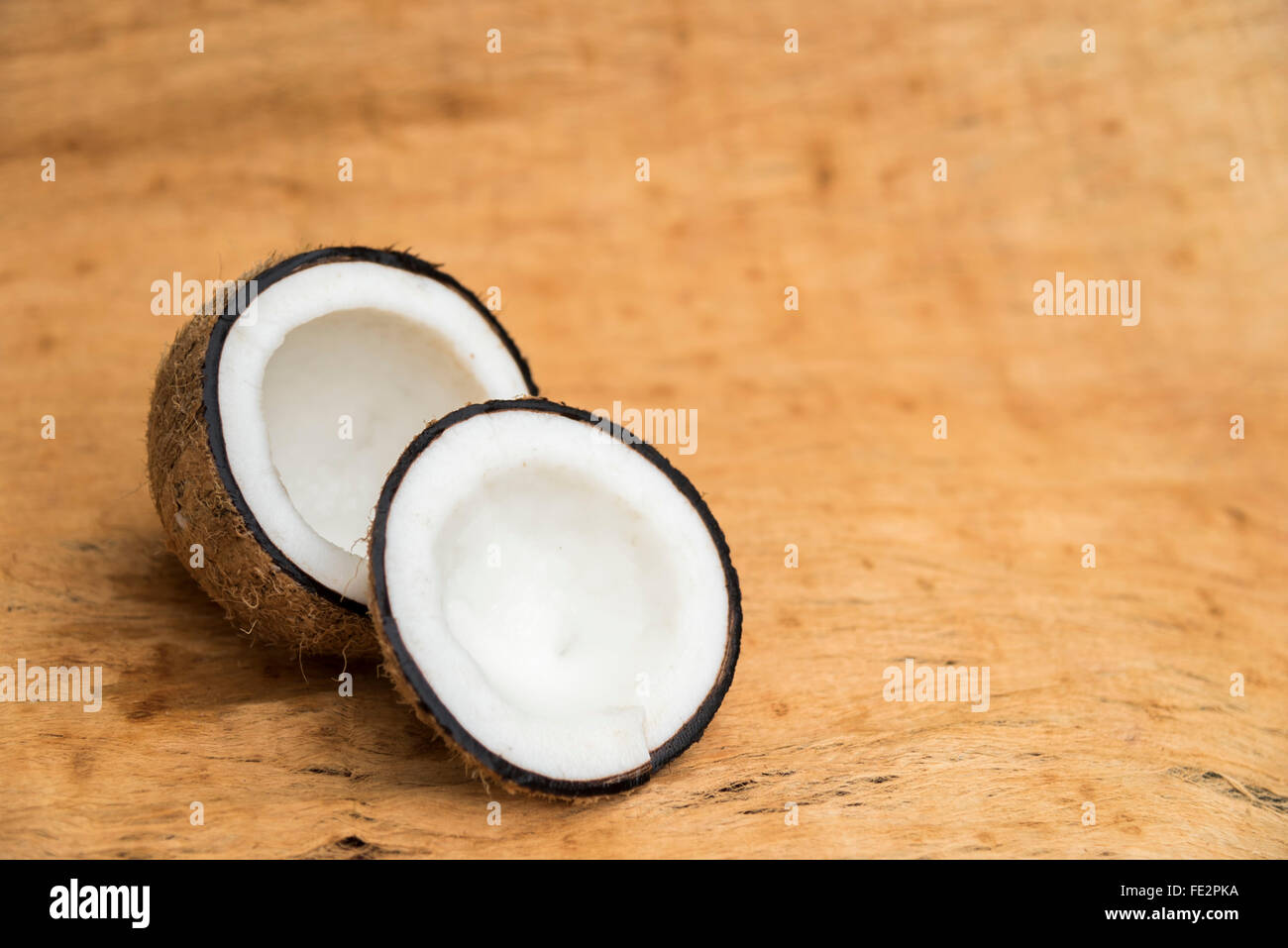 Old coconut cut on wooden background in two parts with negative space Stock Photo