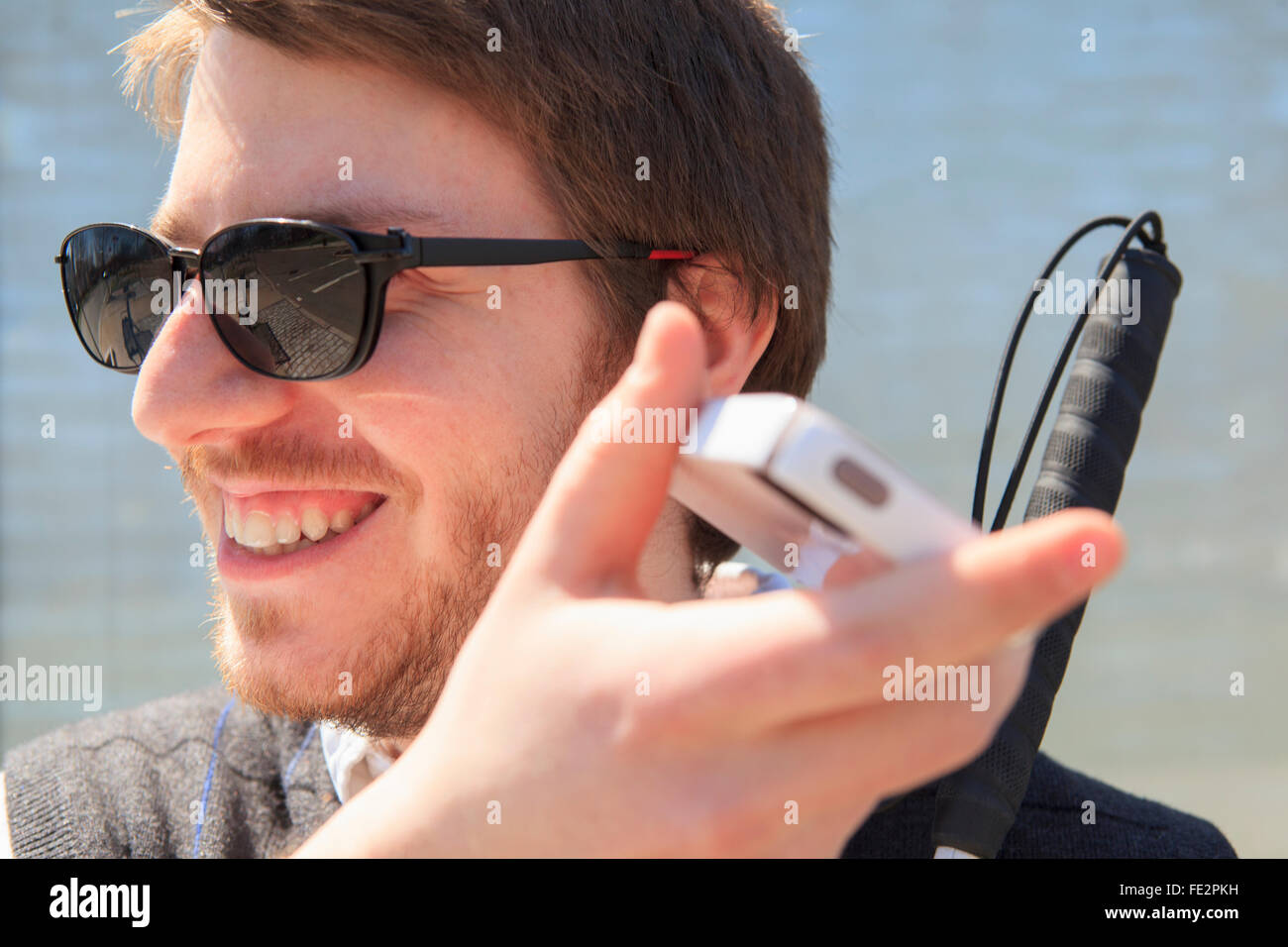 Young blind man with cane using assistive technology Stock Photo