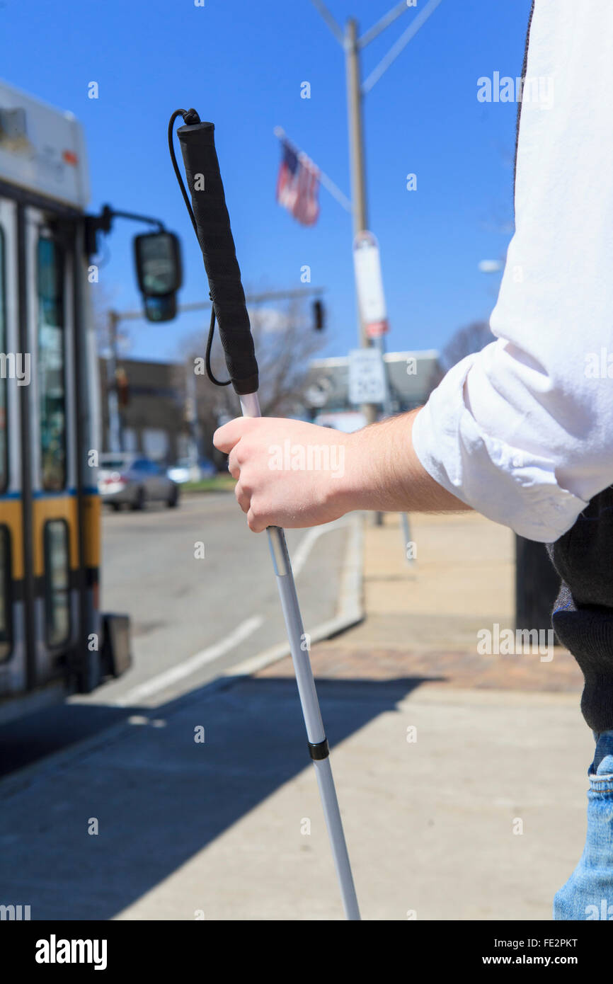 Young blind man with cane waiting at a bus stop Stock Photo