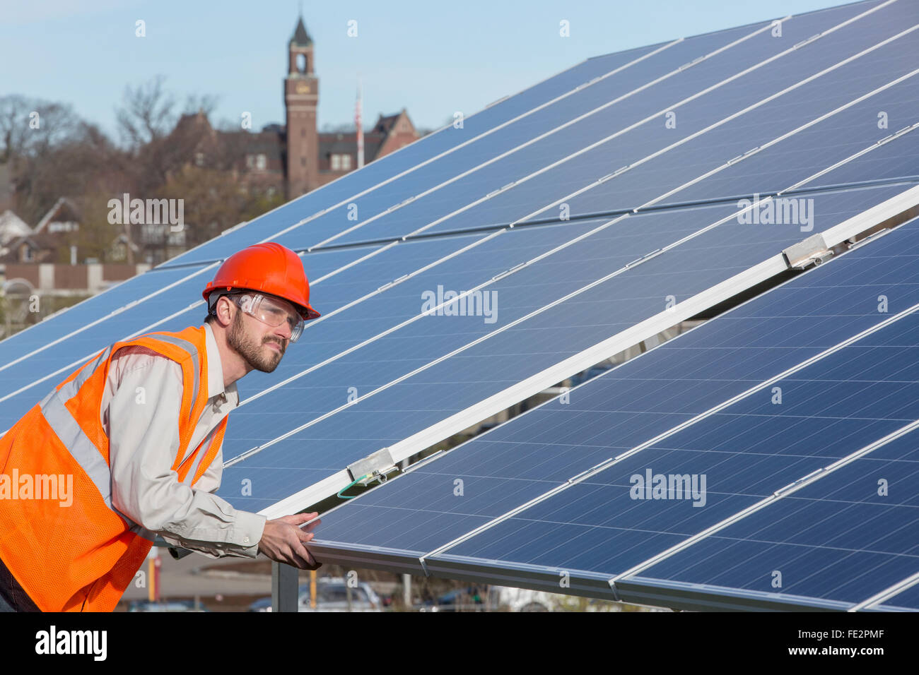 Power engineer at solar photovoltaic array examining surface of panels Stock Photo