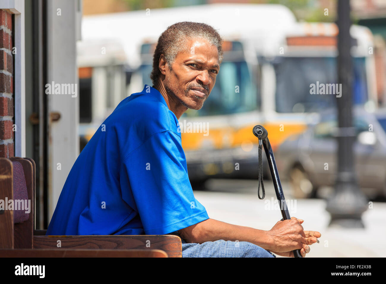 Man with Traumatic Brain Injury relaxing with his cane near the bus