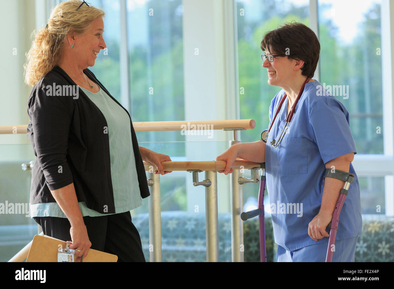 Two nurses in a health clinic, one on canes with Cerebral Palsy Stock Photo