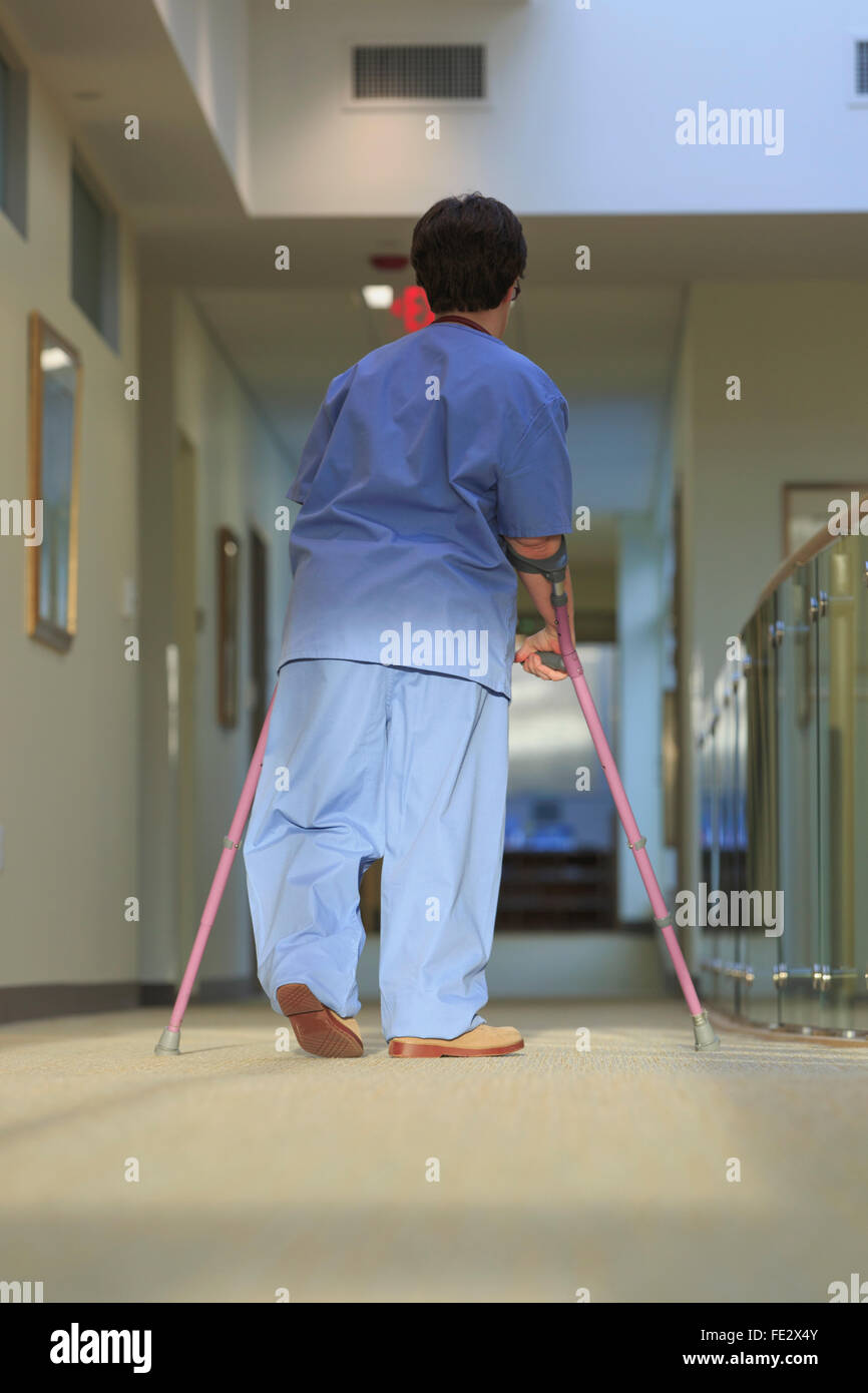 Nurse with Cerebral Palsy walking down the hallway of a clinic with her canes Stock Photo