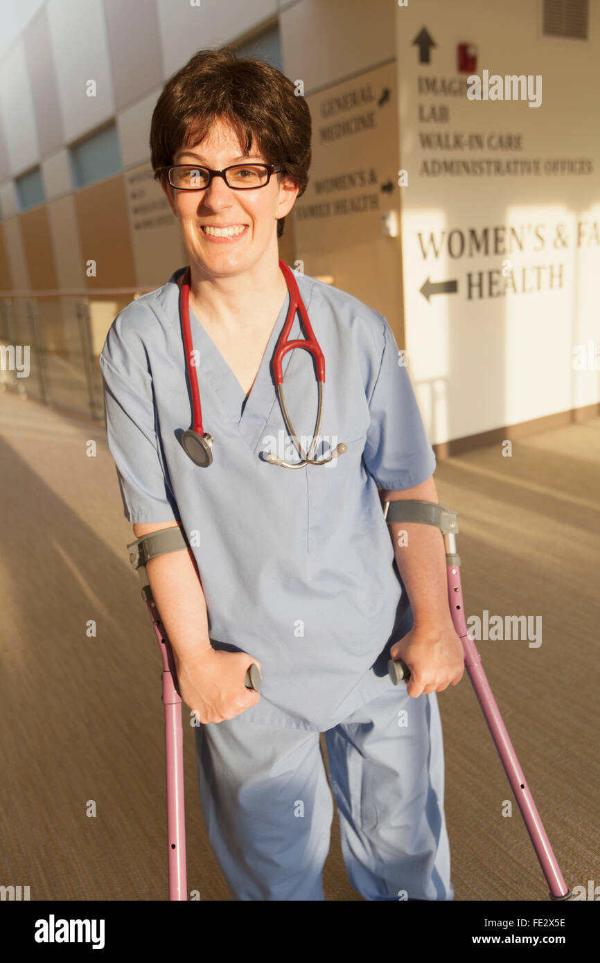 Nurse with Cerebral Palsy walking down the hallway of a clinic with her canes Stock Photo