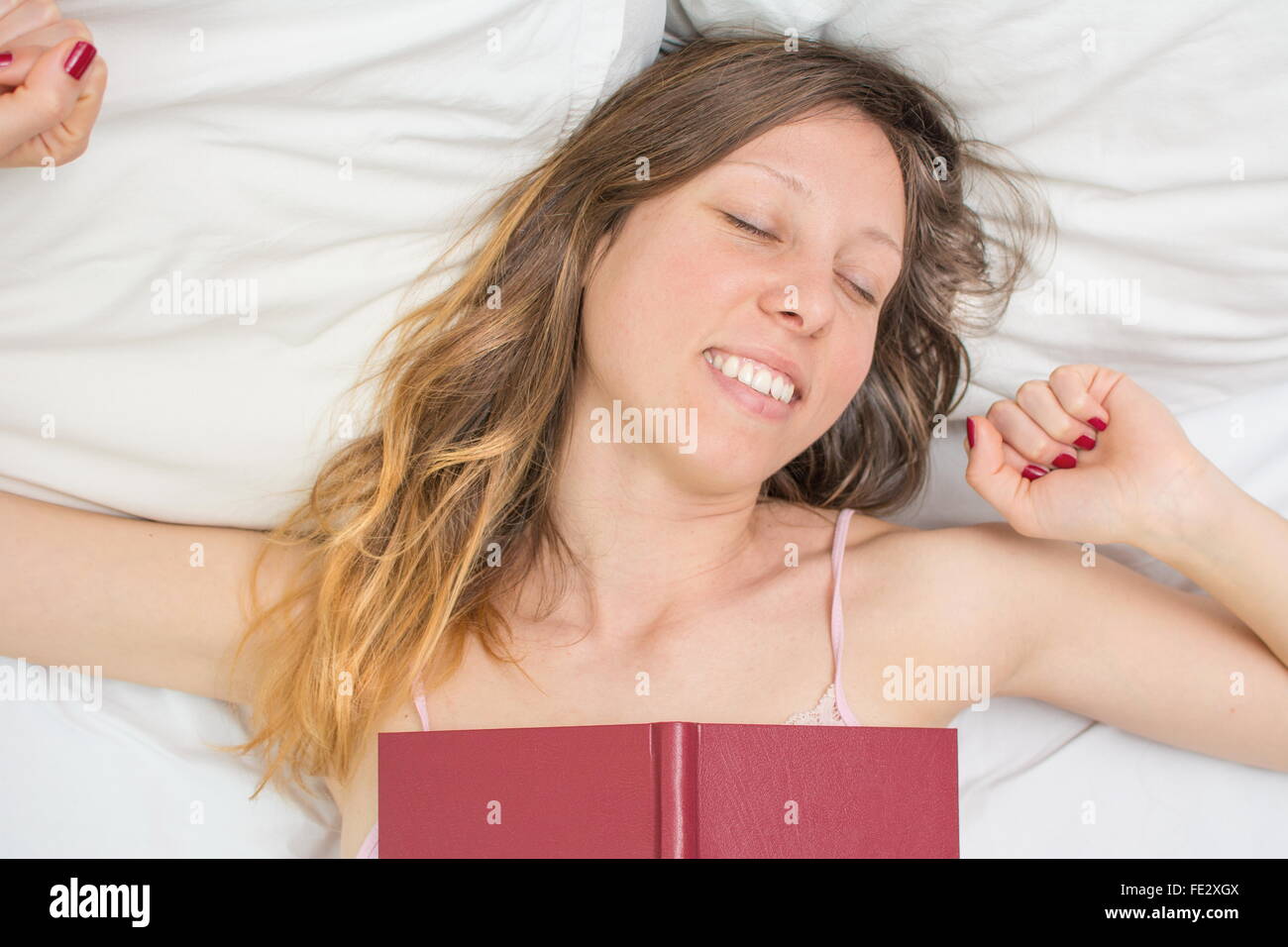 Sleepy girl waking up with a book on her chest Stock Photo