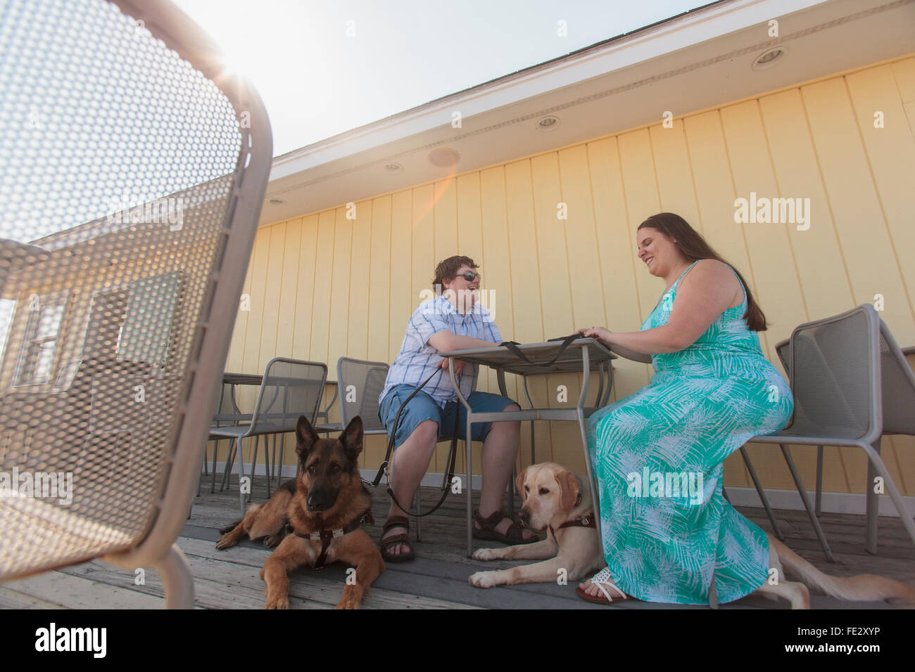 Blind couple and their service dogs sitting at an outdoor cafe Stock Photo