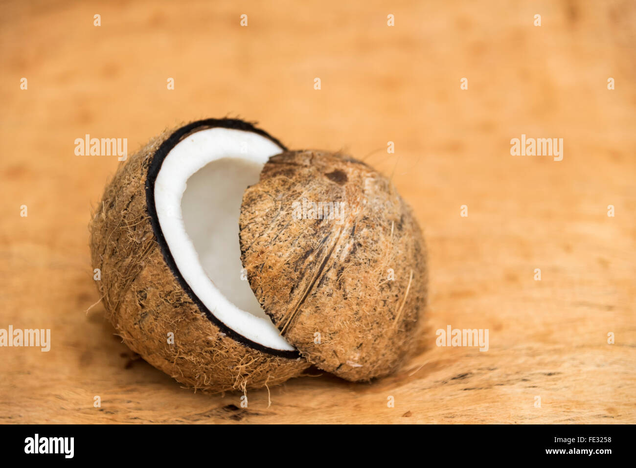 Old coconut cut on wooden background in two parts with negative space Stock Photo
