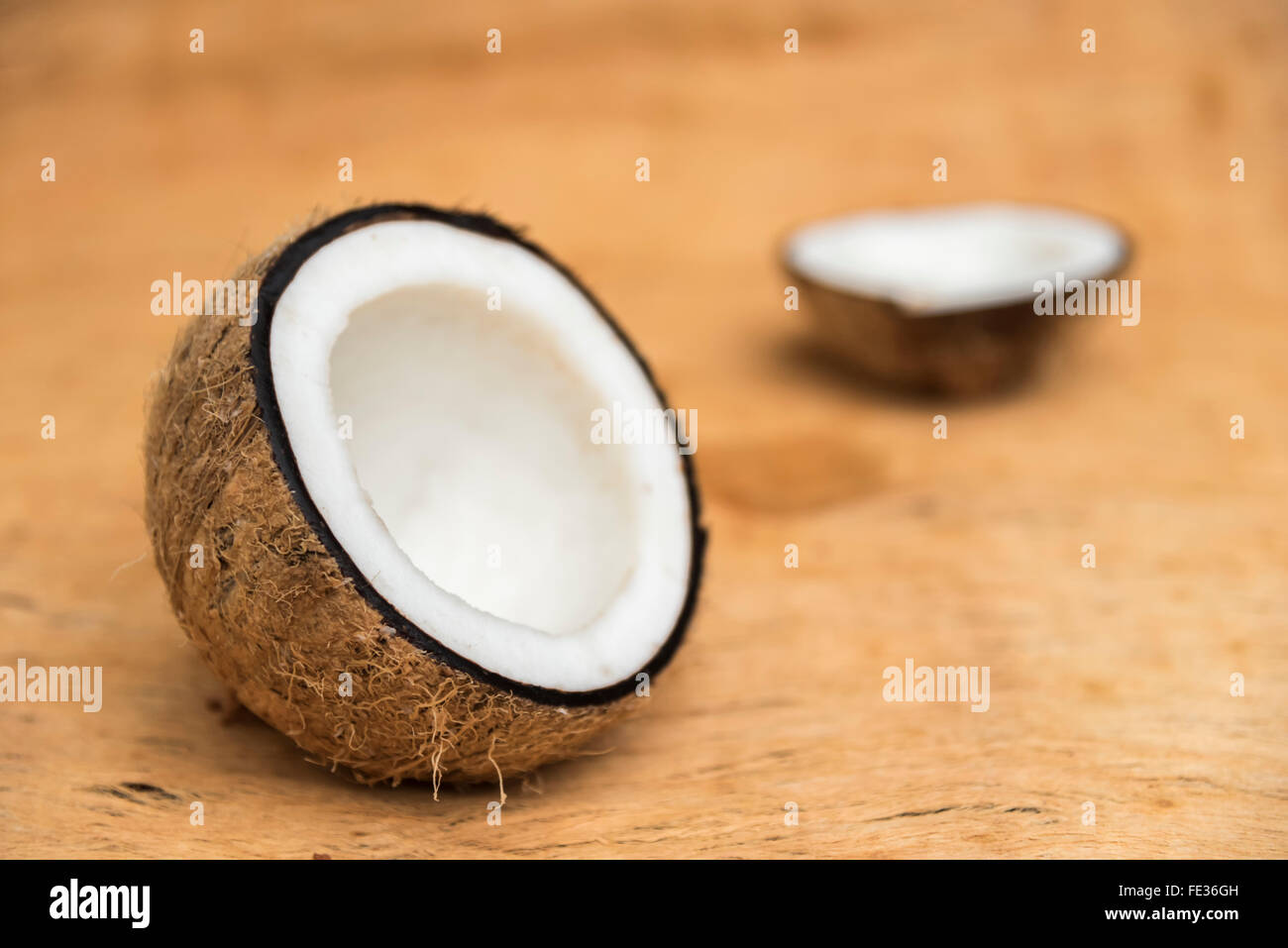 Old coconut cut on wooden background in two parts with negative space Stock Photo
