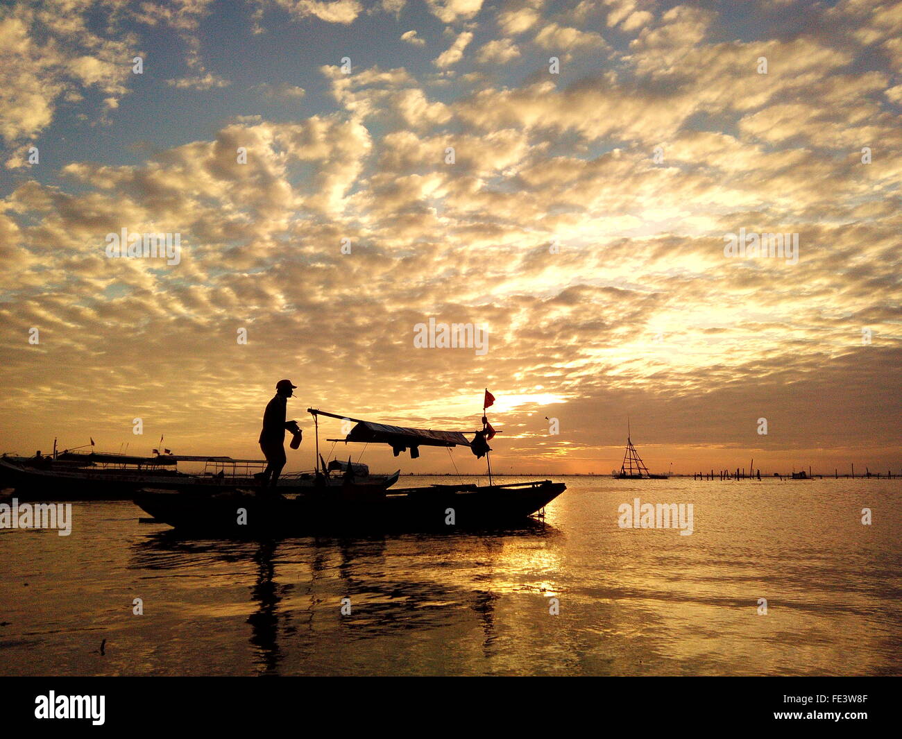 Silhouette Man On Boat Against Cloudy Sky During Sunset Stock Photo