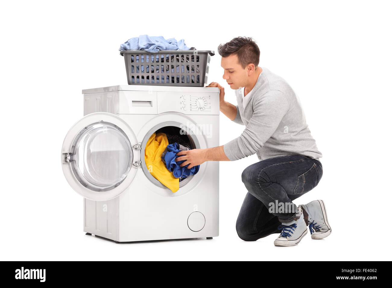 Young man putting clothes in a washing machine isolated on white background Stock Photo