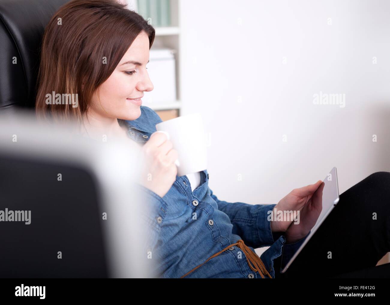 Close up Pretty Young Office Woman Relaxing on her Office Chair with a Cup of Coffee and a Tablet Computer Stock Photo