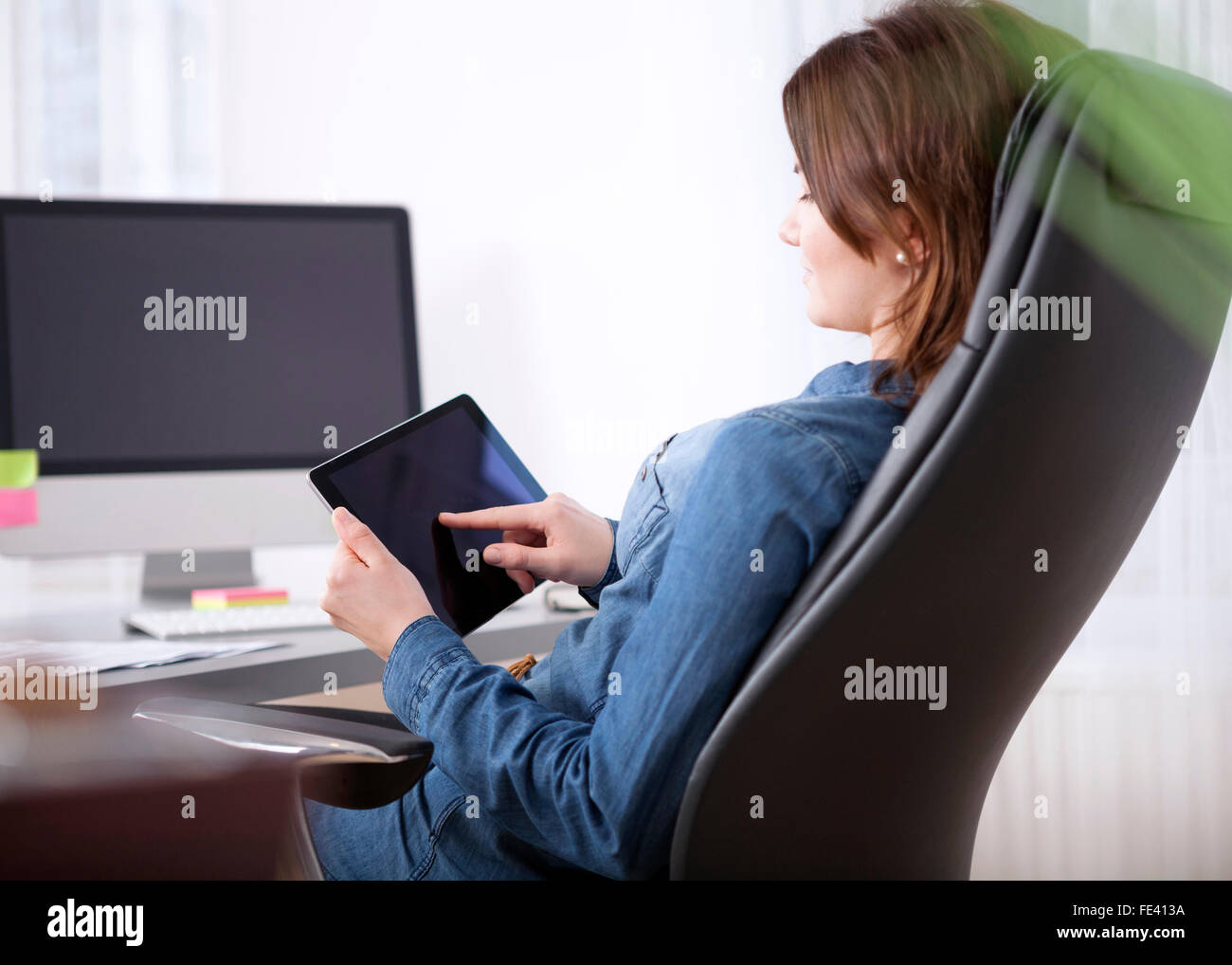 Close up Side View of an Office Woman Sitting at her Worktable Busy Browsing at her Tablet Computer Stock Photo