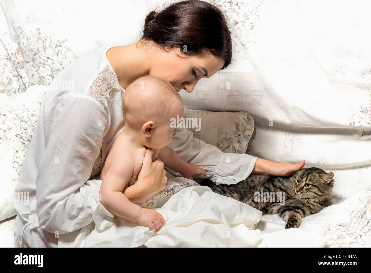 portrait of mother and baby , who stroked a kitten . Home atmosphere . Retro Stock Photo