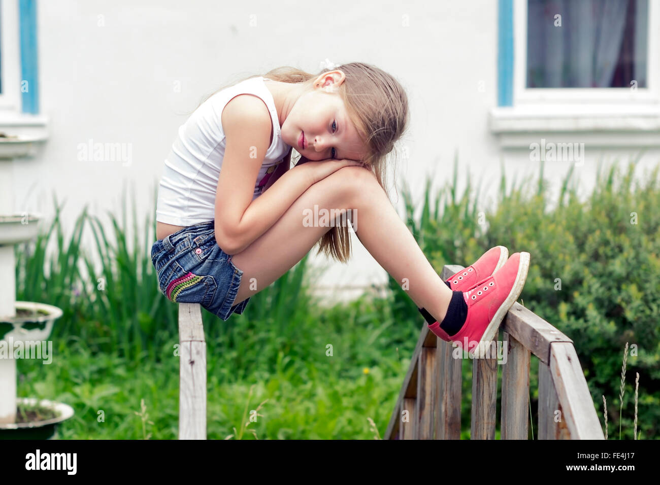 Dreaming girl sitting alone on the bridge. Outdoors. Stock Photo