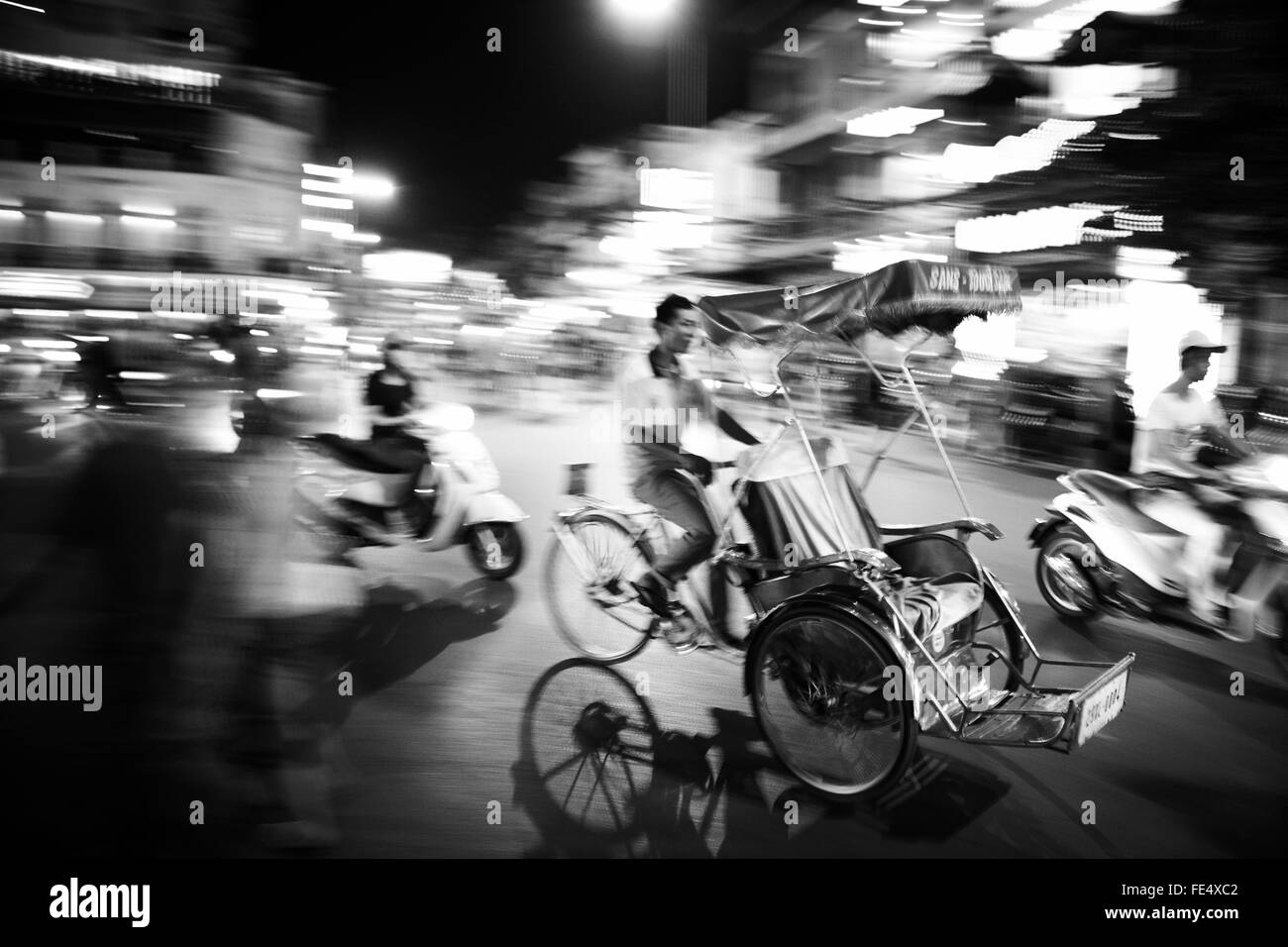 in a jungle of Hanoi, the tuk-tuk drive fast in the center of Hanoi, it's a start of night and every body move. Stock Photo
