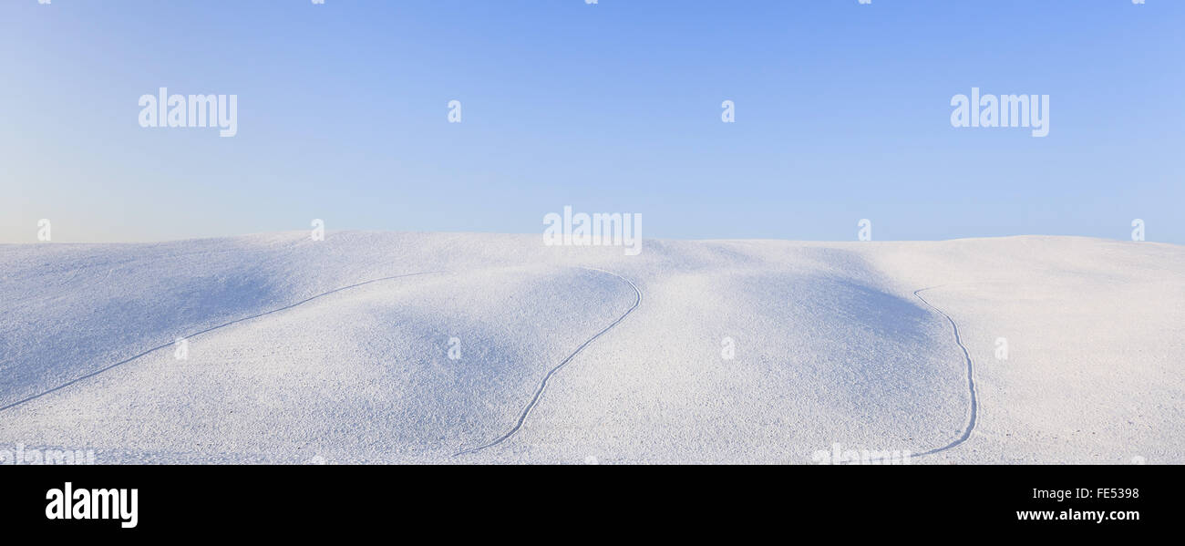 Panoramic snow rolling hills landscape in winter and blue clear sky. Tuscany, Italy. Stock Photo