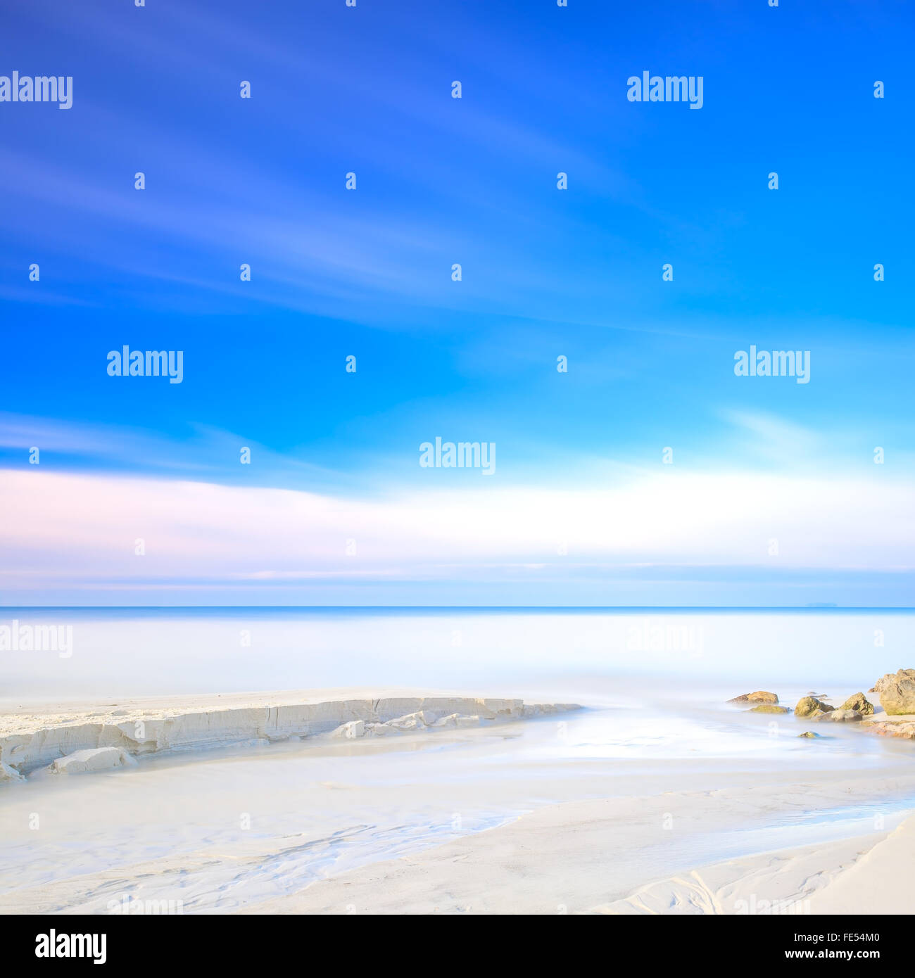 White sand dunes beach, rocks, blue ocean and sky on background Stock Photo